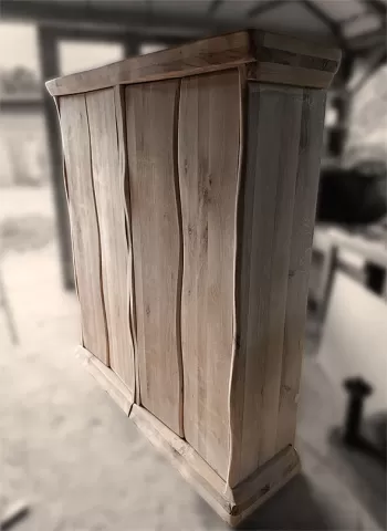 Handcrafted solid oak wine cabinet with unique live edge wavy doors and natural wood grain texture, photographed in a woodworking workshop.